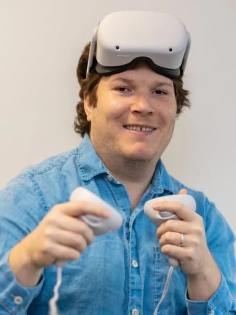 BearHammer Games studio director Brian Allen with a VR headset on his forehead and controllers in hand