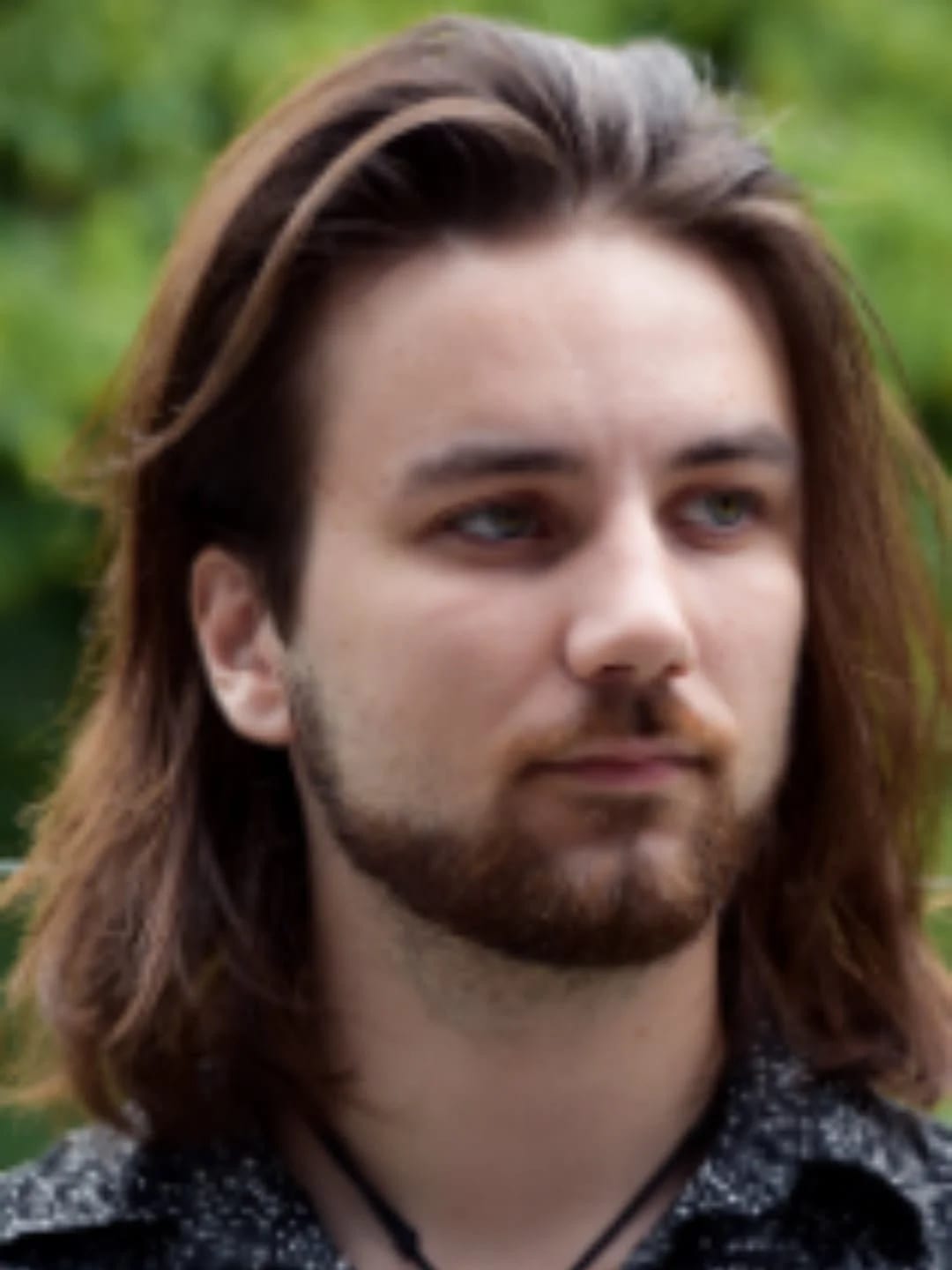 Portrait of BearHammer Games creative lead Connor Shine outdoors in front of green foliage