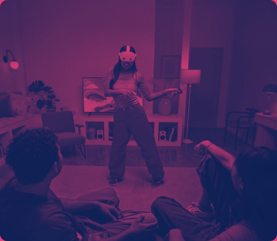 Player in a VR headset standing in a living room while two friends watch from the floor