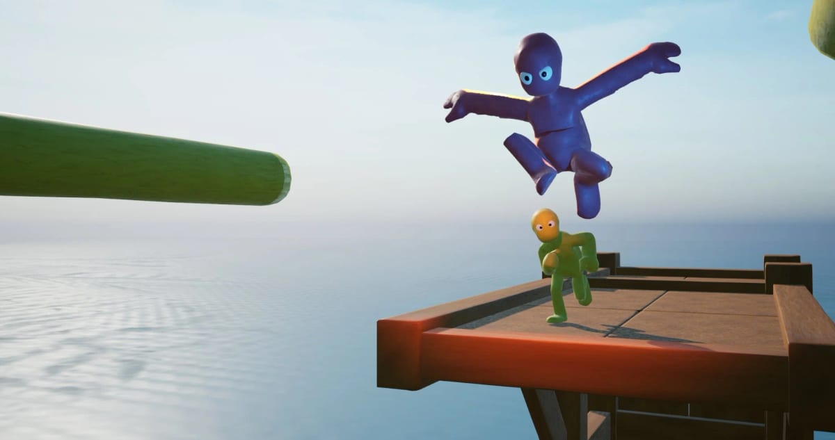 Blue clay character leaping midair over a green one on a wooden platform above the sea